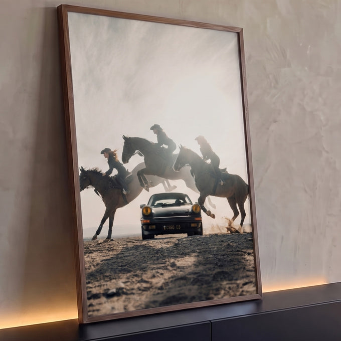 Três cowgirls em cavalos saltando ao redor de um Porsche preto clássico no deserto, quadro decorativo
