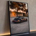 Porsche 911 cinza grafite rebaixado com rodas bronze ao pôr do sol diante de muro, quadro decorativo