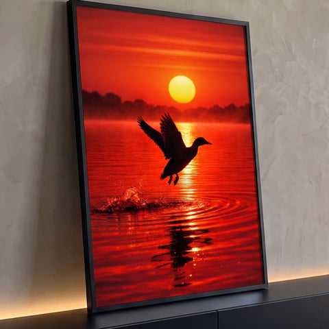 Pato em silhueta decolando de lago com respingos sob sol amarelo e céu vermelho, quadro decorativo