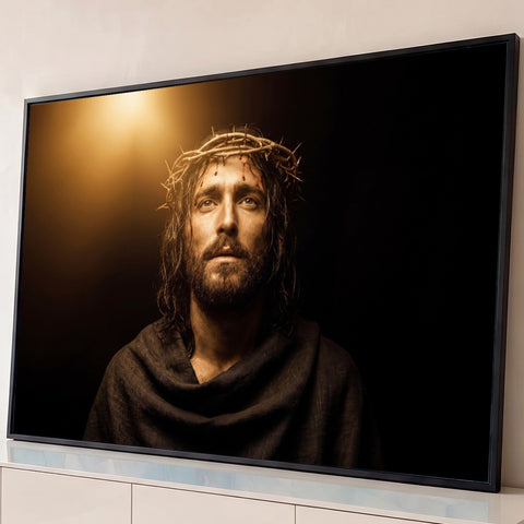 Jesus com coroa de espinhos e manto escuro olhando para luz dourada em fundo preto, quadro decorativo
