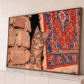 Gatinho rajado de olhos azuis entre parede de pedra e tapete persa vermelho e azul, quadro decorativo