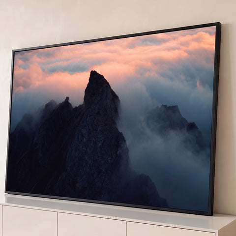 Pico de montanha escuro entre nuvens e neblina com céu rosado ao entardecer, quadro decorativo