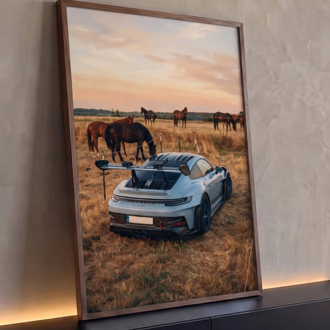 Porsche GT3 RS prata em campo de grama seca com cavalos pastando ao pôr do sol, quadro decorativo