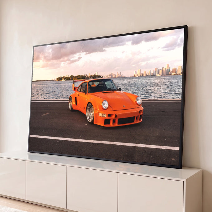 Porsche 911 clássico laranja à beira-mar com o skyline de Miami ao entardecer, quadro decorativo