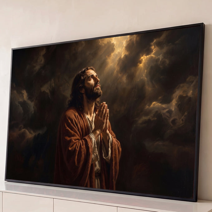 Jesus Cristo de manto marrom orando de mãos unidas sob raios de luz entre nuvens escuras, quadro decorativo