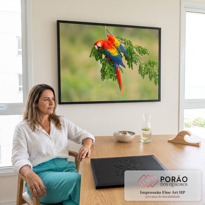 Arara vermelha de asas amarelas e azuis pousada em galho com folhas verdes e fundo desfocado, quadro decorativo