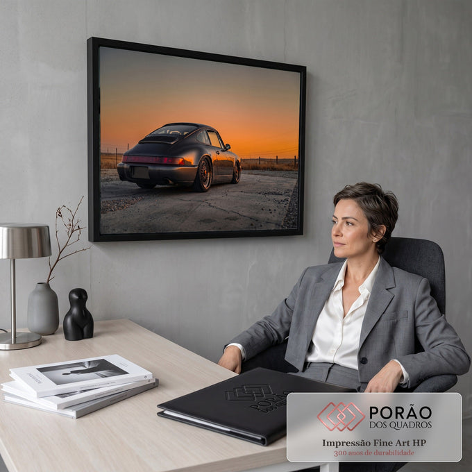 Porsche 911 cinza visto de trás sob céu laranja do pôr do sol em campo seco, quadro decorativo