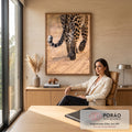 Close das patas e cauda malhada de leopardo caminhando sobre areia clara em tons bege, quadro decorativo