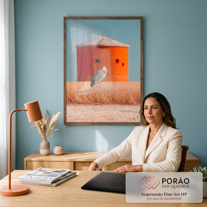 Garça-cinzenta em campo de grama dourada com silo laranja e céu azul ao fundo, quadro decorativo