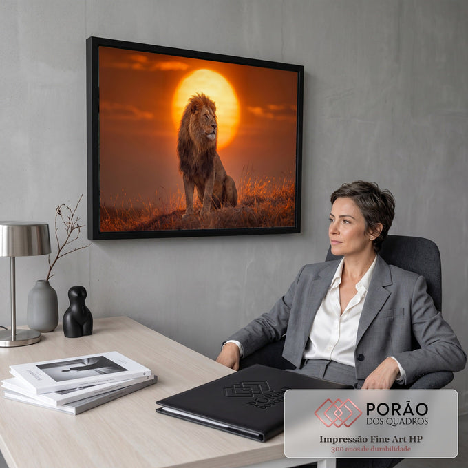 Leão de juba longa sentado no capim seco diante de um grande sol alaranjado na savana, quadro decorativo