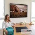 Cavalo de crina loira pastando em campo com manada ao fundo e céu nublado, quadro decorativo