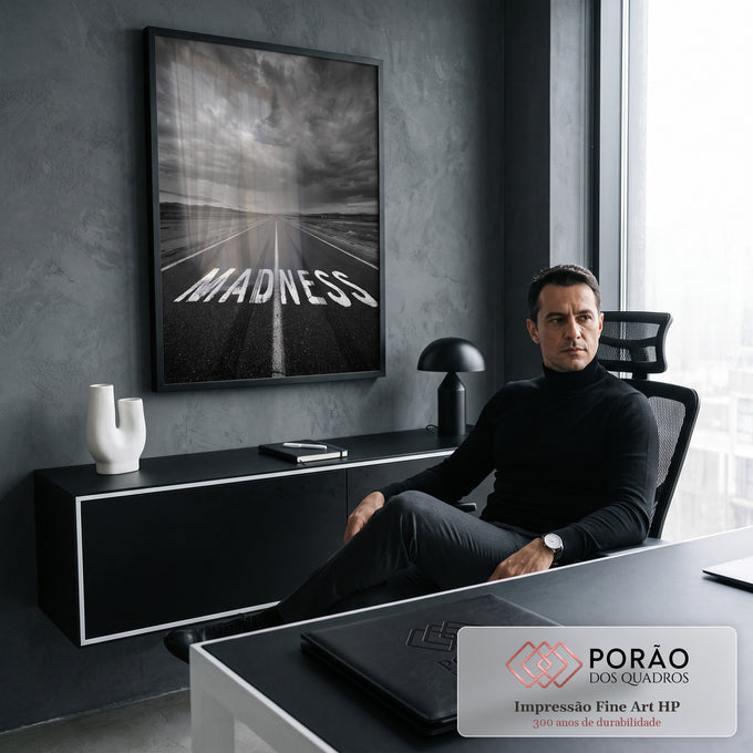 Estrada com a palavra MADNESS pintada no asfalto sob céu tempestuoso em preto e branco, quadro decorativo