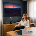 Pôr do sol laranja sobre colinas ondulantes com pinheiros em silhueta e lua crescente, quadro decorativo