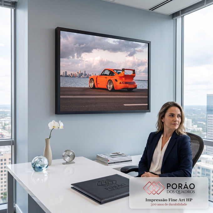 Porsche 911 laranja com aerofólio à beira-mar, prédios da cidade e nuvens rosadas ao fundo, quadro decorativo