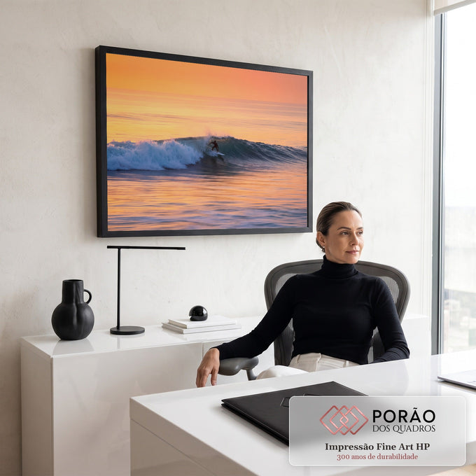 Surfista deslizando numa onda azul no mar ao pôr do sol, com céu laranja e reflexos dourados, quadro decorativo