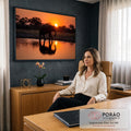 Elefante em silhueta caminhando à beira do lago com reflexo ao pôr do sol laranja, quadro decorativo