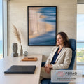 Praia vista do alto com mar azul em movimento, areia bege e duas pessoas caminhando, quadro decorativo