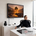 Quadro Decorativo Grande Árvore Solitária Rio para Sala | quadros decorativos | árvore solitária sobre pedras à beira de rio com sol poente entre galhos e montanhas ao fundo | em ambiente 2 | Porao dos Quadros