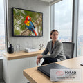 Arara-vermelha ajeitando as penas num tronco com folhagem verde desfocada ao fundo, quadro decorativo