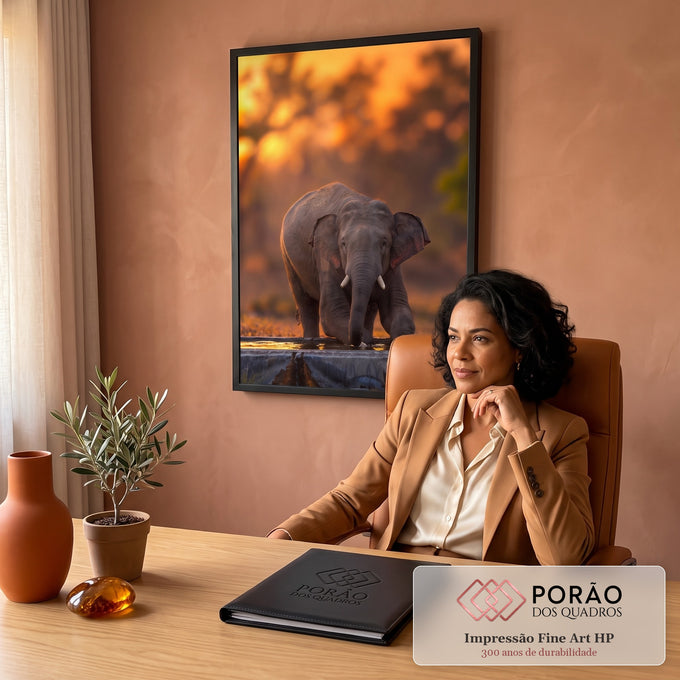 Elefante jovem ajoelhado bebendo água em bebedouro com fundo laranja de pôr do sol, quadro decorativo