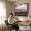 Porsche 911 laranja com aerofólio à beira-mar, skyline e céu nublado ao entardecer, quadro decorativo