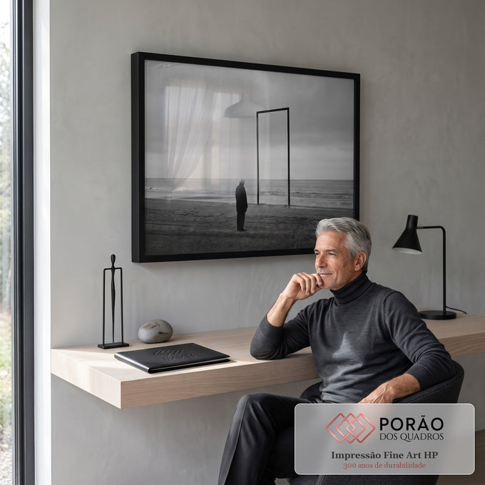 Homem idoso diante de portal metálico na praia sob céu nublado, em preto e branco, quadro decorativo