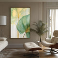 Folhas verde e amarela com hastes douradas em aquarela sobre fundo creme, quadro decorativo
