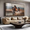 Três cavalos marrons galopando na água em campo dourado com montanhas ao fundo, quadro decorativo