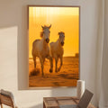 Dois cavalos brancos galopando na areia com céu dourado de pôr do sol ao fundo, quadro decorativo
