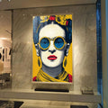 Quadro Decorativo - Frida Kahlo Energizante em Amarelo | quadros decorativos para sala | Mulher em pop art com óculos redondos azuis, flores amarelas acima, paleta vibrante. | Porao dos Quadros