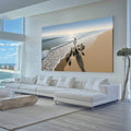 Quadro Decorativo Jesus Harmonia à Beira do Mar | quadros decorativos para sala | Surfista caminhando na praia ao entardecer com sombra alongada e ondas ao fundo | Porao dos Quadros