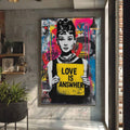 Quadro Decorativo Love é a Resposta | quadros decorativos para sala | Mulher em preto e branco com cartaz amarelo 'Love is Answer' em fundo pop art colorido com magenta, azul e padrões abstratos. | Porao dos Quadros
