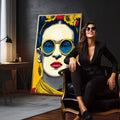 Quadro Decorativo - Frida Kahlo Energizante em Amarelo | quadros decorativos para sala | Mulher em pop art com óculos redondos azuis, flores amarelas acima, paleta vibrante. | em Quadros para Sala | Porao dos Quadros
