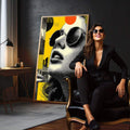 Quadro Decorativo Mulher Sob a Luz Amarela | quadros decorativos para sala | Mulher com óculos redondos em retrato preto e branco com elementos geométricos amarelos vibrantes | em Quadros para Sala | Porao dos Quadros