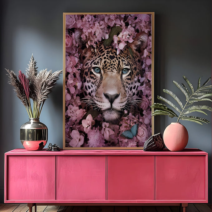 Rosto de onça pintada com olhos azuis cercado por flores rosas e folhas verdes, quadro decorativo