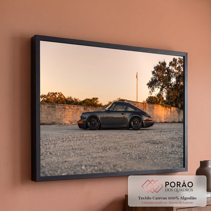 Porsche 911 clássico cinza rebaixado de perfil ao pôr do sol, sobre cascalho e muro, quadro decorativo