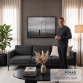 Homem idoso diante de portal metálico na praia sob céu nublado, em preto e branco, quadro decorativo