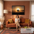 Silhueta de cowboy galopando a cavalo em contraluz ao pôr do sol com poeira dourada, quadro decorativo