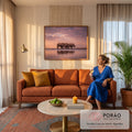 Três rinocerontes caminhando sob céu rosa ao pôr do sol, refletidos na água calma, quadro decorativo