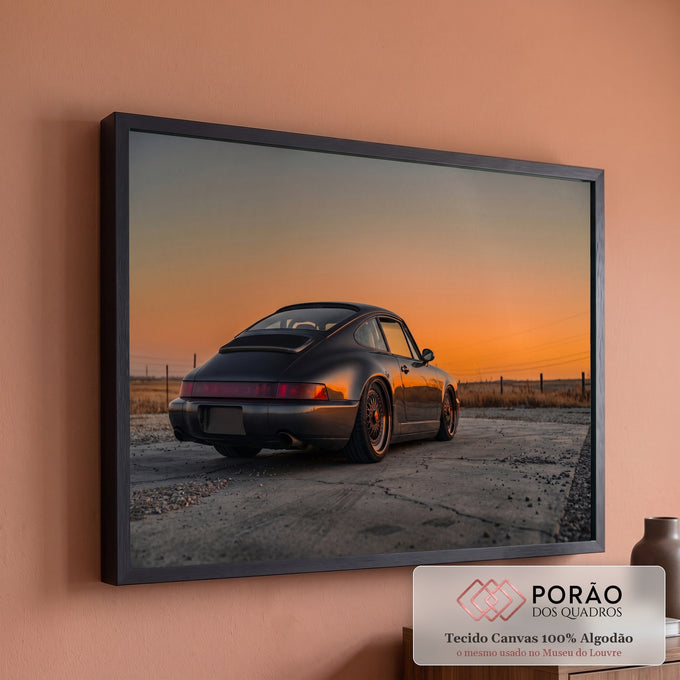 Porsche 911 cinza visto de trás sob céu laranja do pôr do sol em campo seco, quadro decorativo