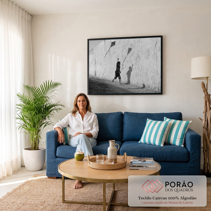 Menino descalço correndo com pipa junto a muro rachado, sombra na parede, foto P&B, quadro decorativo