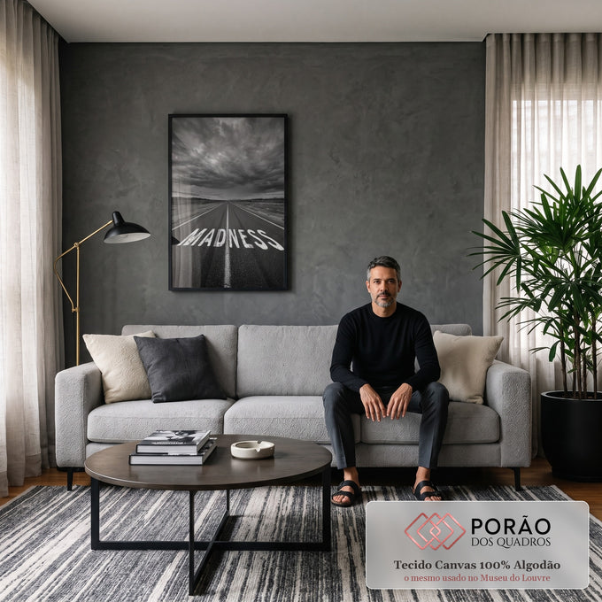 Estrada com a palavra MADNESS pintada no asfalto sob céu tempestuoso em preto e branco, quadro decorativo