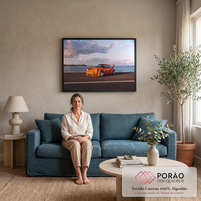 Porsche 911 clássico laranja com aerofólio à beira-mar, skyline e céu com nuvens, quadro decorativo