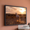Cavalo branco trotando em picadeiro de areia ao pôr do sol, levantando poeira sob céu laranja, quadro decorativo