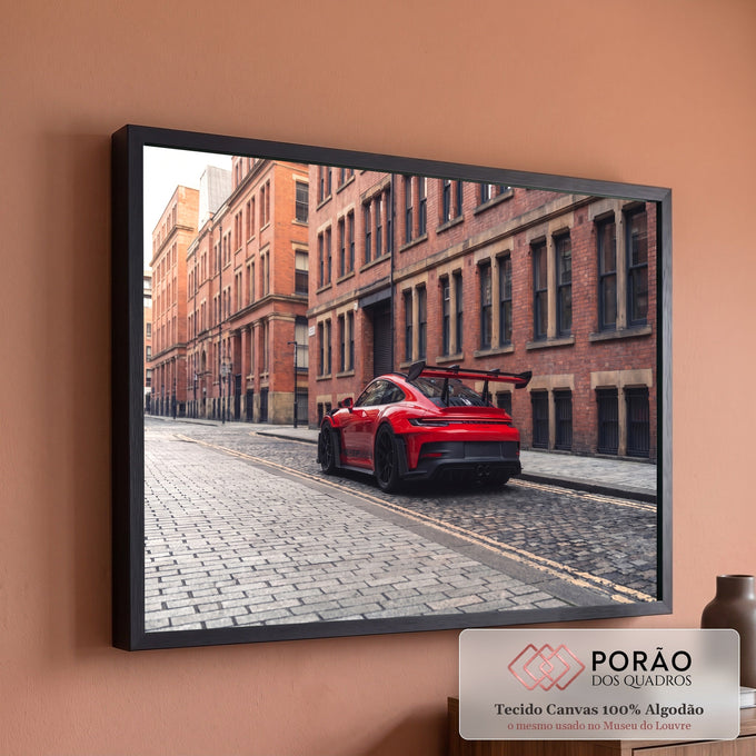 Porsche 911 GT3 RS vermelho com aerofólio em rua de pedras entre prédios de tijolo, quadro decorativo